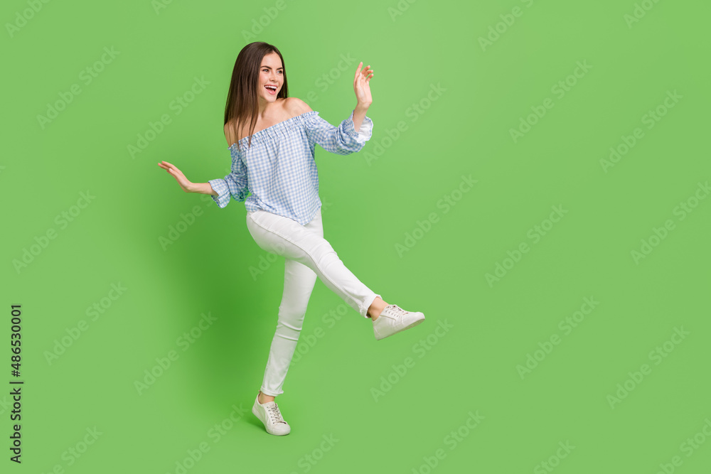 Full size photo of adorable girl in casual wear look empty space dancing make big step isolated on green color background Full size photo of adorable girl in casual wear look empty space dancing make big step isolated on green color background