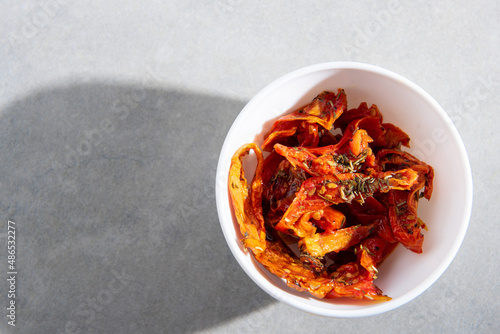 dried tomatoes with spices in a white plate on a gray concrete background