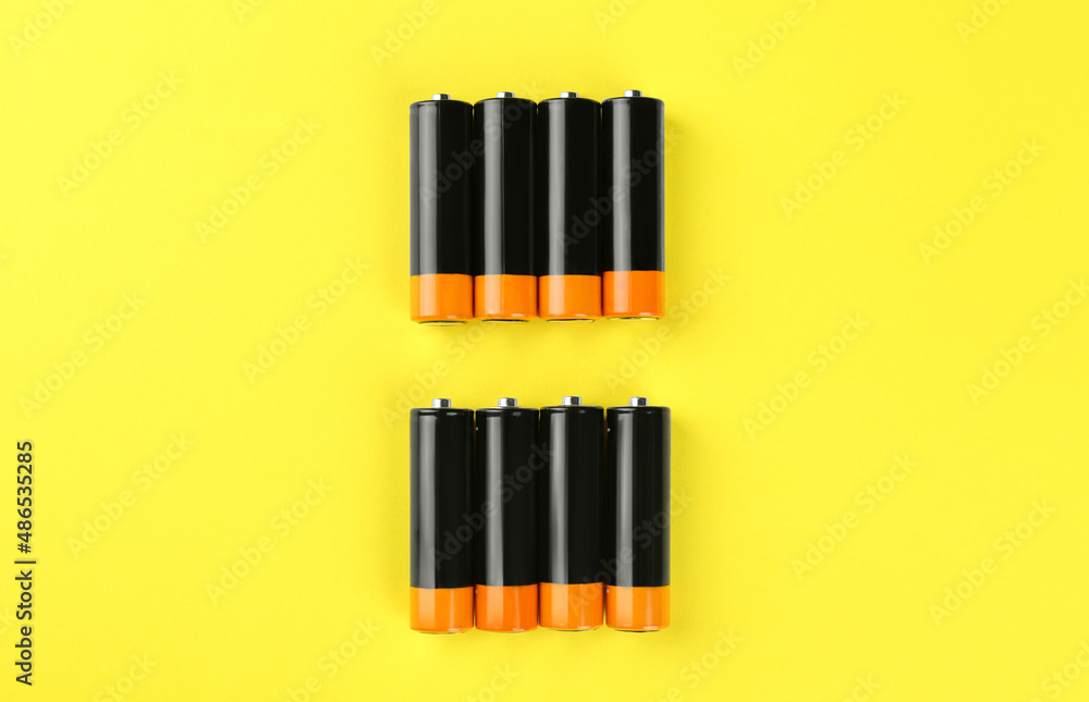 New AA batteries on yellow background, flat lay New AA batteries on yellow background, flat lay