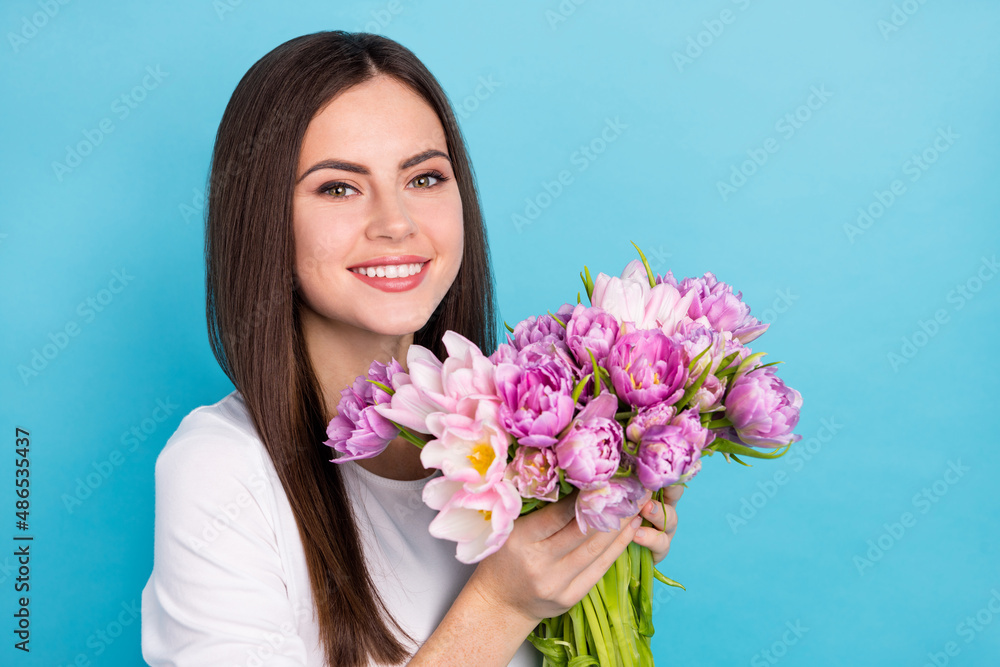 Portrait of charming positive lady receive peony and tulips flowers from her boyfriend isolated on blue color background Portrait of charming positive lady receive peony and tulips flowers from her boyfriend isolated on blue color background