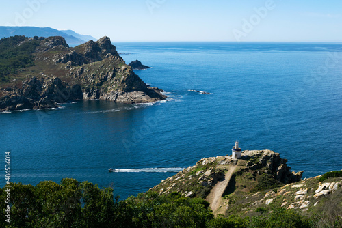 Boat sailing past a lighthouse and the south island of the Cies Islands, Galicia, Spain photo