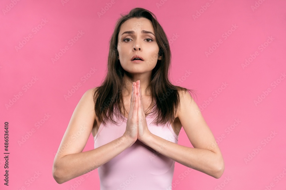 Begging for help or praying worried woman with hands put together looking in camera with help need in her eyes. Hopeful religious woman in hope for forgiveness Begging for help or praying worried woman with hands put together looking in camera with help need in her eyes. Hopeful religious woman in hope for forgiveness