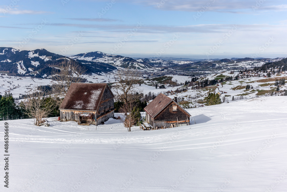Isolated summer chalet and farm stables high up on the Swiss Alps covered in fresh powder snow near Bruelisau in Appenzell