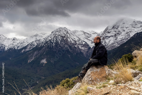 A man sitting on a stone in the mountains in winter