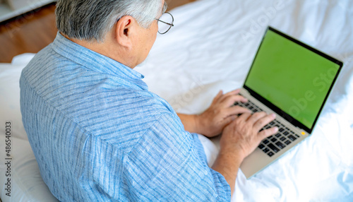 Happy old man positive, Portrait Asian Senior man and eyeglasses using computer laptop in bedroom at home, Old elderly male Technology communication retirement lifestyles concept.
