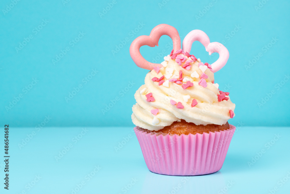 trendy cupcake with sprinkles on blue background, concept of St. Valentines Day, copy space trendy cupcake with sprinkles on blue background, concept of St. Valentines Day, copy space