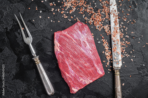 Uncooked Raw flap flank beef meat steak on kitchen table. Black background. Top view