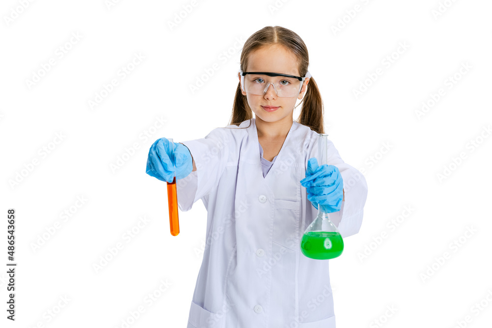 One serious little school girl, kid in white big gown as chemist, scientist doing experiment with multicolored chemical fluid in laboratory isolated on white background One serious little school girl, kid in white big gown as chemist, scientist doing experiment with multicolored chemical fluid in laboratory isolated on white background