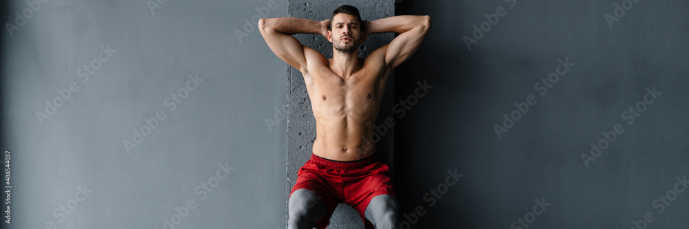Young shirtless sportsman doing exercise with expander stretch tape Young shirtless sportsman doing exercise with expander stretch tape