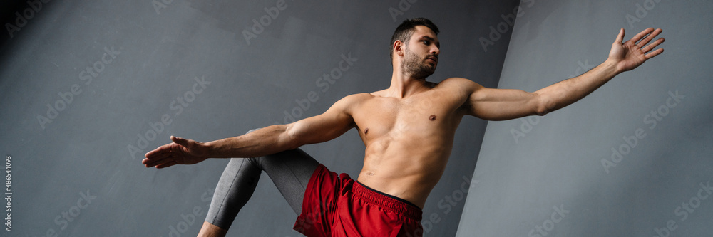 Obraz premium Young shirtless sportsman doing exercise with sport equipment indoors