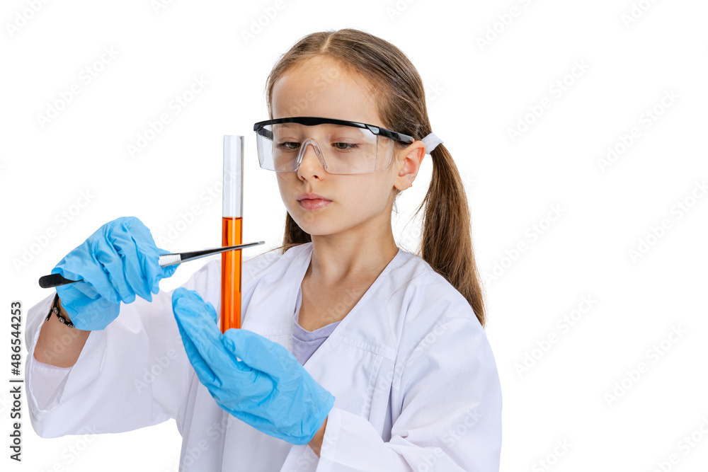 One serious little school girl, kid in white big gown as chemist, scientist doing experiment with multicolored chemical fluid in laboratory isolated on white background One serious little school girl, kid in white big gown as chemist, scientist doing experiment with multicolored chemical fluid in laboratory isolated on white background