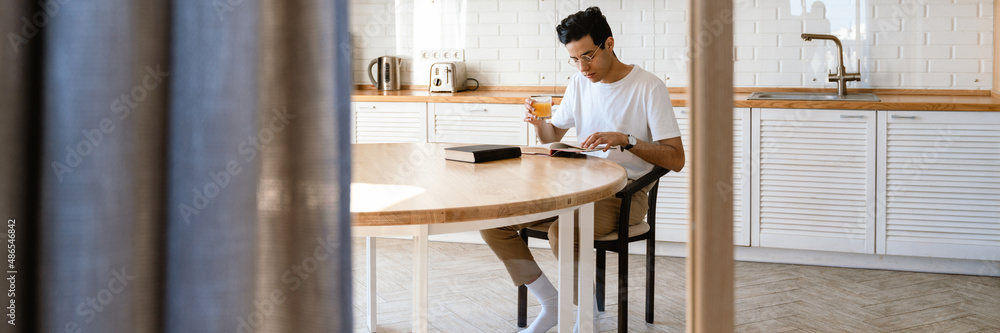 Young hispanic man reading a book while having breakfast Young hispanic man reading a book while having breakfast