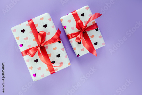 Gift boxes wrapped in heart pattern paper with red ribbon bow on pink background