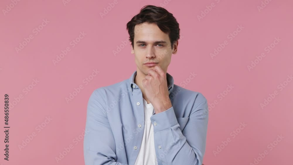 Fun insighted smart proactive pensive young brunet man 20s wears blue shirt looks around thinks scratches at temple comes up with ideas raised finger isolated on plain pink background studio portrait Fun insighted smart proactive pensive young brunet man 20s wears blue shirt looks around thinks scratches at temple comes up with ideas raised finger isolated on plain pink background studio portrait