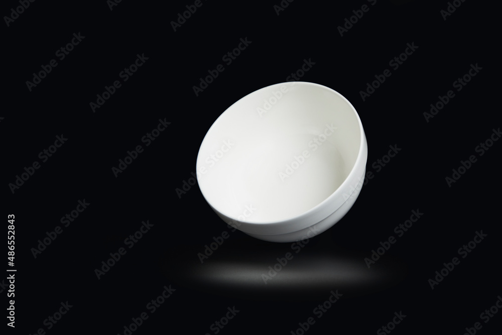 White bowl with notch on black background with reflection below. White bowl with notch on black background with reflection below.