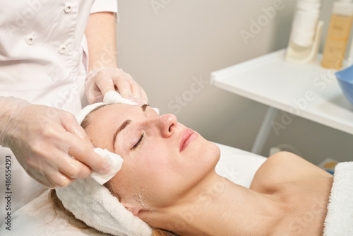 Face massage prepare at spa salon. Doctor hands. Pretty female patient. Beauty treatment. Healthy skin procedure. Young woman head. Cleaning rejuvenation. Facial dermatology mask. Detox therapy