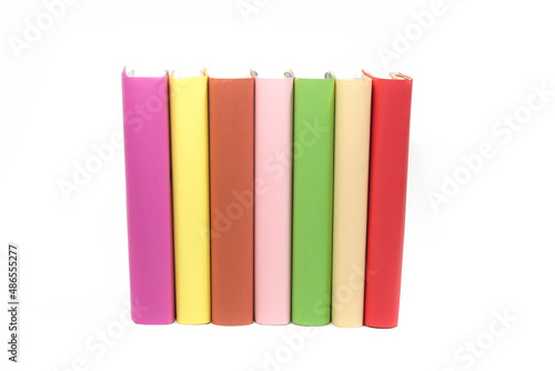 Many books of different colors stand in a row on a white background, insulator