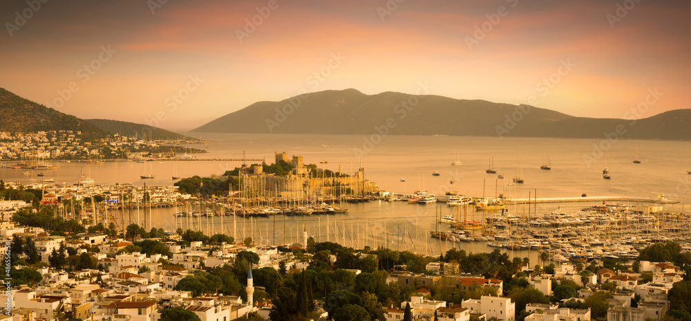 Fototapeta premium Top view of the sea with yacht in Bodrum harbor. City landscape with St. Peter's castle at sunset. Turkey's most important travel and holiday destination.