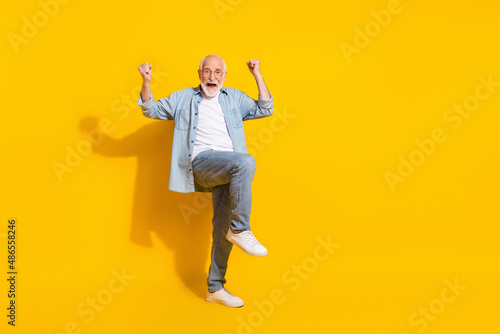 Full length body size view of attractive funky cheerful grey-haired man rejoicing great news isolated over bright yellow color background photo
