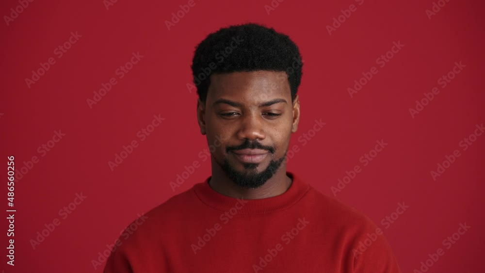 Positive African man looking at the camera in the red studio Positive African man looking at the camera in the red studio