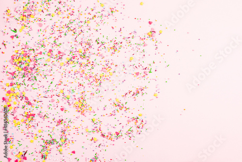 Colorful sprinkles on pink background, top view. Confectionery decor. Multicolor confectionery topping dressing. Festive background