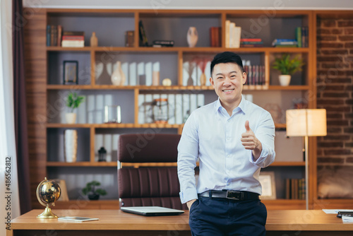 Portrait of a successful university principal, Asian teacher in a shirt looks at the camera and smiles, keeps his finger up, encourages young people to study at the university photo