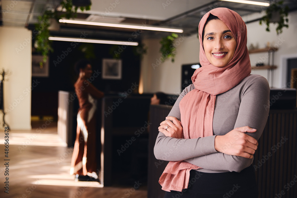Obraz premium Portrait of confident young Middle Eastern woman smiling and looking at camera in coworking space