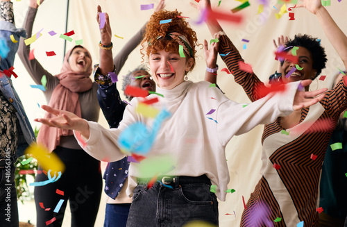 Action shot of young white woman celebrating International Women's Day with friends and ticker tape