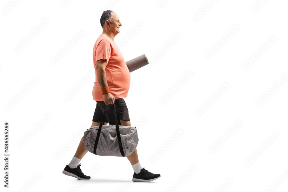 Naklejka premium Full length profile shot of a mature man in sportswear walking with a sports bag and exercise mat