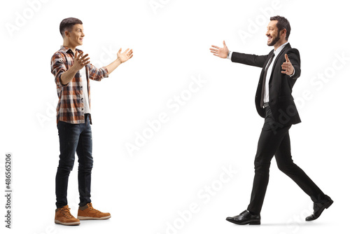 Full length profile shot of a casual young man and a businessman greeting with arms wide open
