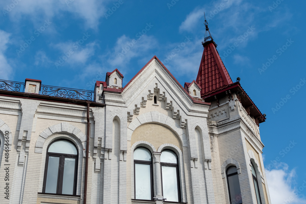 Fototapeta premium Top floor of building with turrets against blue sky. Ukraine, Zhytomyr, February 11, 2022