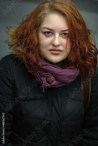 Portrait of a beautiful young plump red-haired girl in spring clothes.