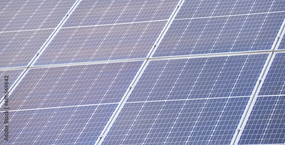 Closeup of building roof with rows of blue solar photovoltaic panels for producing clean ecological electric energy. Renewable electricity with zero emission concept Closeup of building roof with rows of blue solar photovoltaic panels for producing clean ecological electric energy. Renewable electricity with zero emission concept