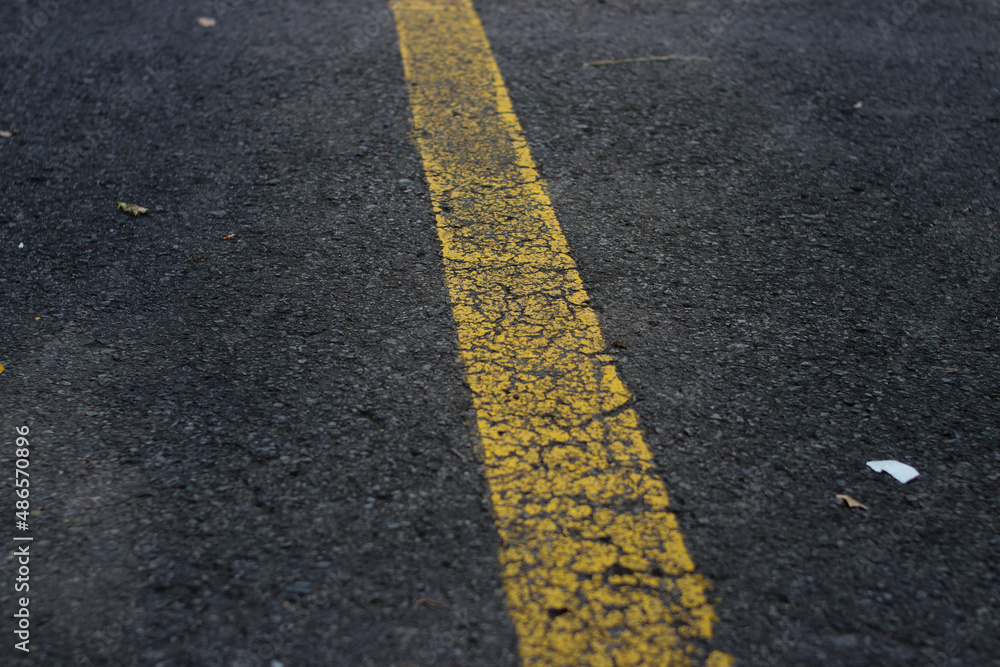 Defocus abstract background with yellow lines on cracked asphalt road in a parking lot. Cracked Asphalt background with yellow line