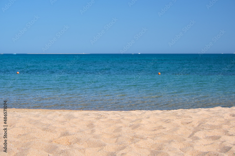 Seascape with surface of blue sea water with small ripple waves crashing on yellow sandy beach. Travel and vacations concept