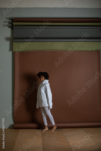 African american woman in a white hoodie and leggings stands on a brown background. Mock-up. © kanashkin