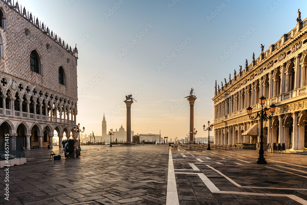 Famous empty San Marco square with Doges Palace at sunrise,Venice,Italy.Early morning in popular tourist destination.World famous Venice landmarks.San Giorgio Maggiore church in background