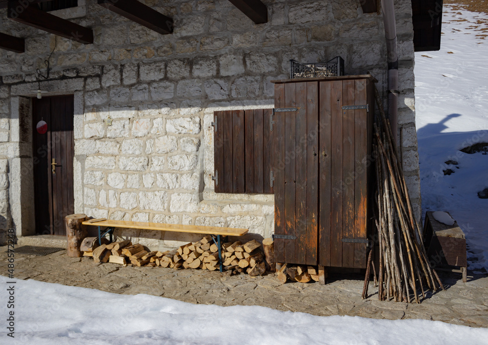 Obraz premium Detail of a mountain house with stone walls and brown wooden shutters.