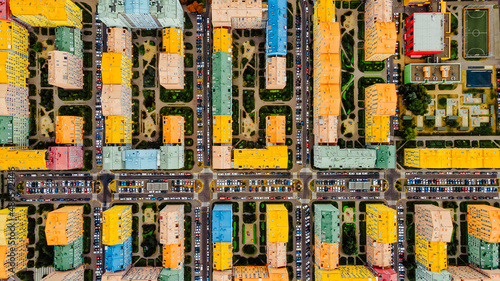 Flying above city buildings. Colourful development of the city. Modern architecture with houses and parkings
