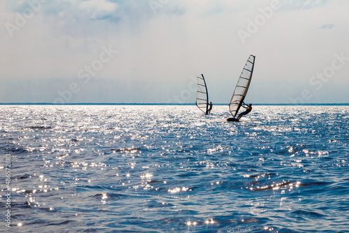 Two men on a horizon on a water sailing windsurfing board. photo