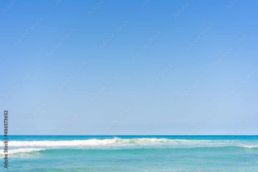 Turquoise sea waves with white scallops under a blue clear sky. Clear weather over the Atlantic. Ocean waves on a sunny summer morning.