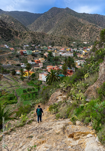 VALLEHERMOSO, LA GOMERA, Kanarische Inseln: Wanderung von einer Frau im Norden der Insel mit Blick von oben auf den pittoresken Ort mit bunten Häusern und den Bergen photo