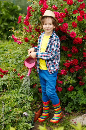 Child with a watering can. Boy takes care of garden plants. Spring work in the garden. Kid helps parents © Miramiska