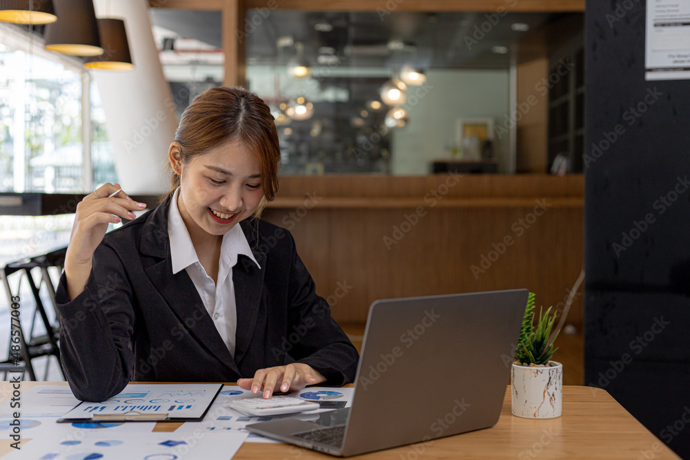 Obraz premium A beautiful Asian businesswoman sitting in her private office, she is checking company financial documents, she is a female executive of a startup company. Concept of financial management.