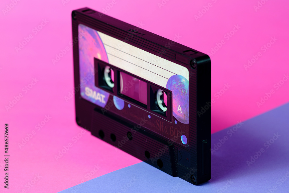 Fototapeta premium Vintage audio cassette isolated in perspective. Pink and purple diagonal background