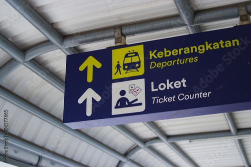 Blue signboard with "Departures" and "ticket counter" text on a train station hallway in a train station in Bandung