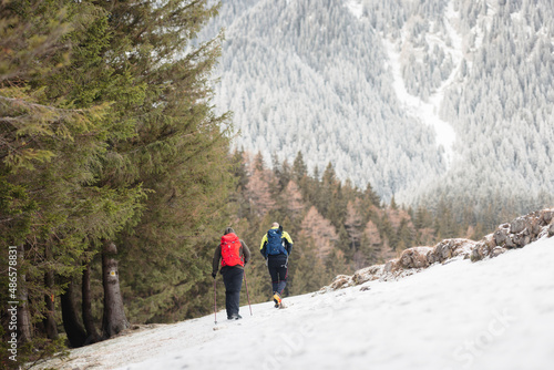 People hiking in beautiful winter mountains for winter sport activity snow mountain hills. Visit Piatra Craiului National Park to see its iconic rocky monolith winter hiking