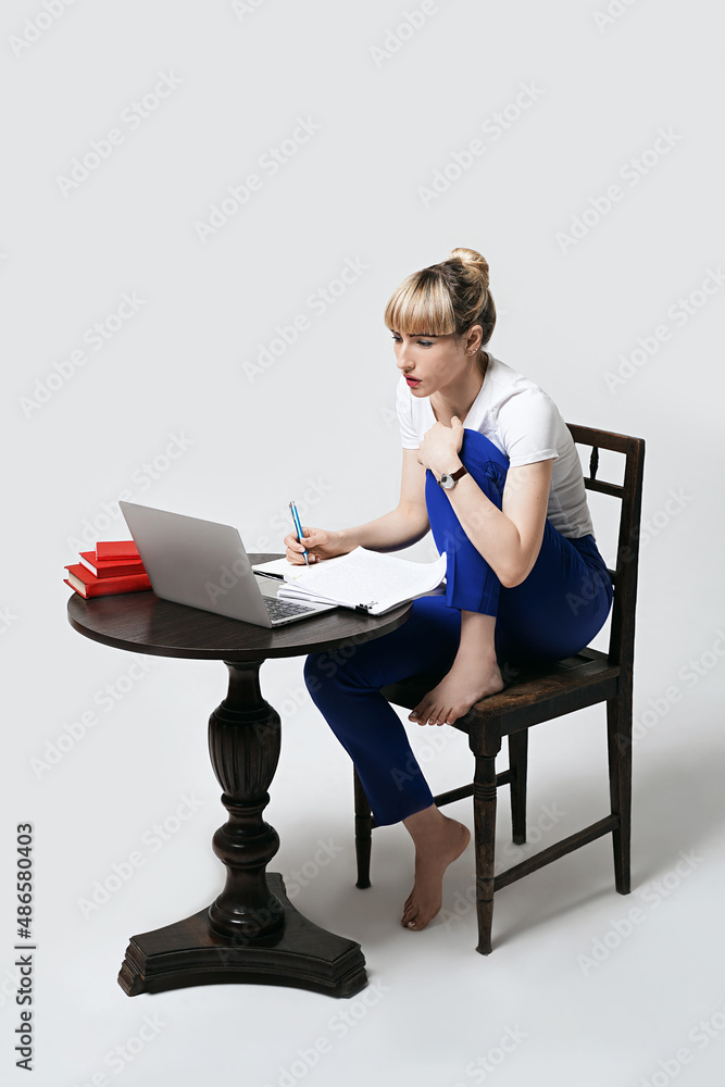 Focused young female student sitting at desk working or studying remotely online making effort to understand the content. Distant learning or remote work from home. Isolated on white background.
