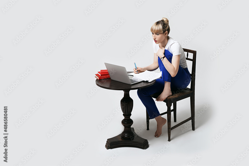Focused young female student sitting at desk working or studying remotely online making effort to understand the content. Distant learning or remote work from home. Isolated on white background.