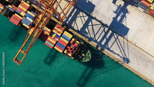 Aerial top down photo of cranes loading - unloading container ship anchored in logistics terminal of Perama near commercial port of Piraeus, Attica, Greece